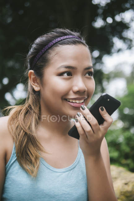 Young asian sporty woman using smartphone in park — Stock Photo