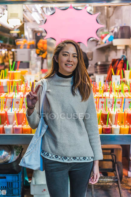 Giovane attraente asiatico donna mostrando pace gesto in negozio — Foto stock