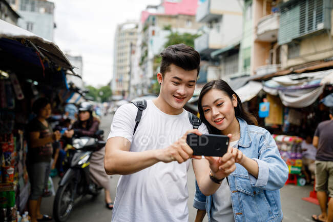 Giovane coppia asiatica utilizzando smartphone in un mercato locale a Ho Chi Minh City, Vietnam. — Foto stock