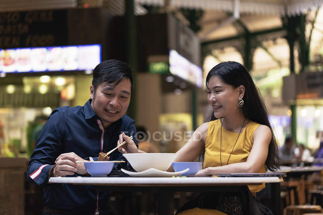 Счастливая азиатская молодая пара вместе едят в кафе — стоковое фото