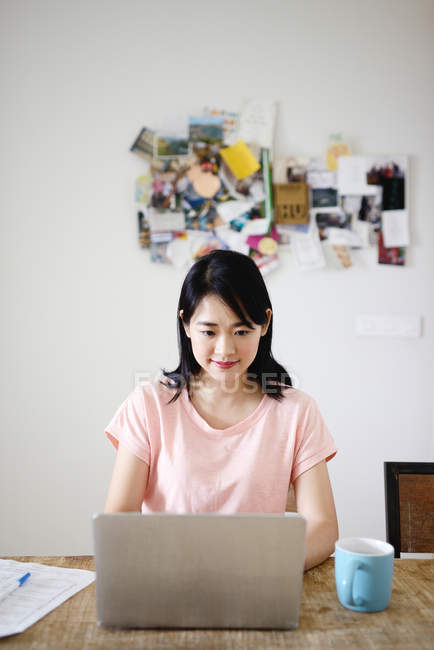 Jovem casual asiático mulher usando laptop em casa — Fotografia de Stock