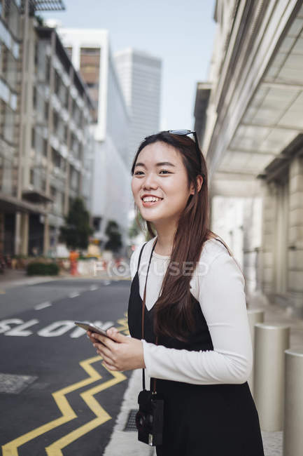 Bella cinese capelli lunghi donna con smartphone sulla strada — Foto stock