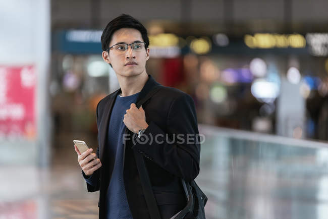 Успішний азіатський бізнесмен використовує смартфон в аеропорту — стокове фото