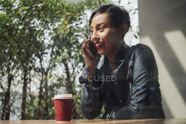 Молодая привлекательная азиатская женщина с помощью смартфона и кофе — стоковое фото