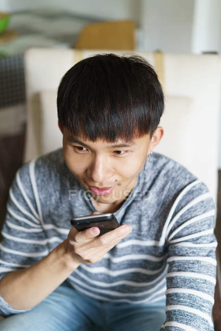 Junge erwachsene asiatische Mann mit Smartphone zu Hause — Stockfoto