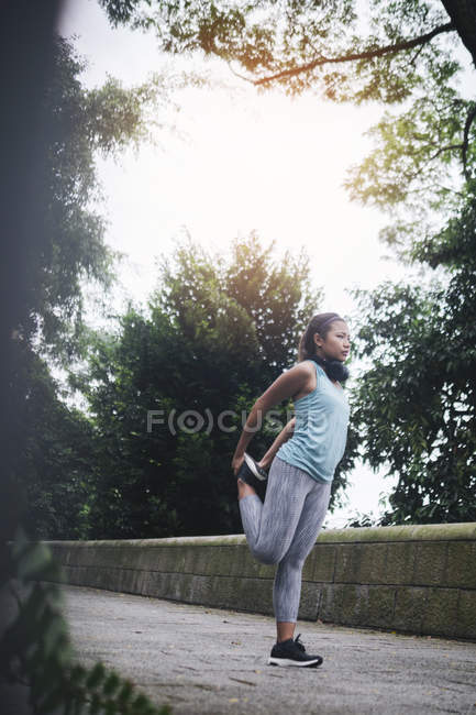 Молода азіатська спортивна жінка робить розтягування в парку — стокове фото