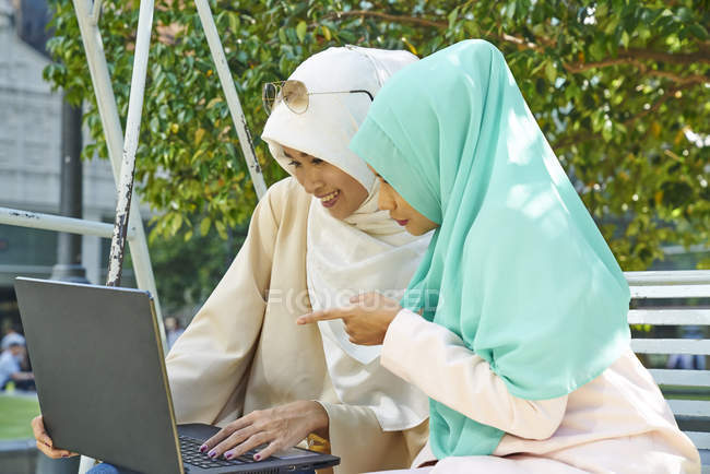 Duas mulheres bonitas em um Tudung trabalhando em um laptop — Fotografia de Stock