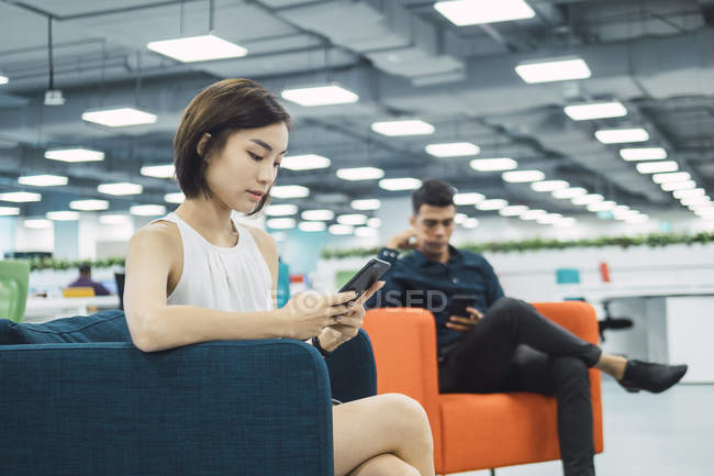 Gente de negocios de éxito utilizando teléfonos inteligentes en la oficina moderna - foto de stock