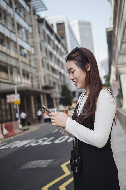 Hübsche Chinesin mit langen Haaren und Smartphone auf der Straße — Stockfoto