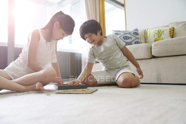Щаслива молода азіатська сім'я разом, діти грають в лайно вдома — стокове фото