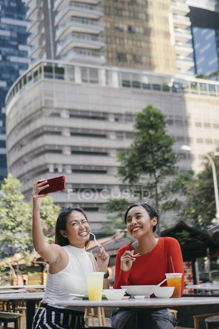 Молодые азиатские подруги вместе делают селфи на городской улице — стоковое фото