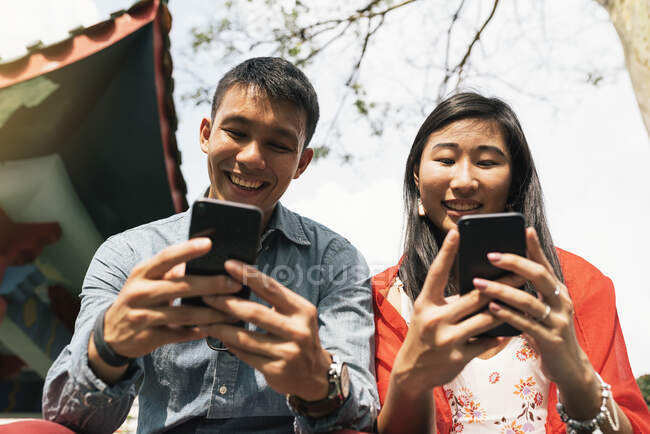 Un couple d'Asiatiques chinois passe du temps ensemble dans le quartier chinois à regarder des smartphones — Photo de stock