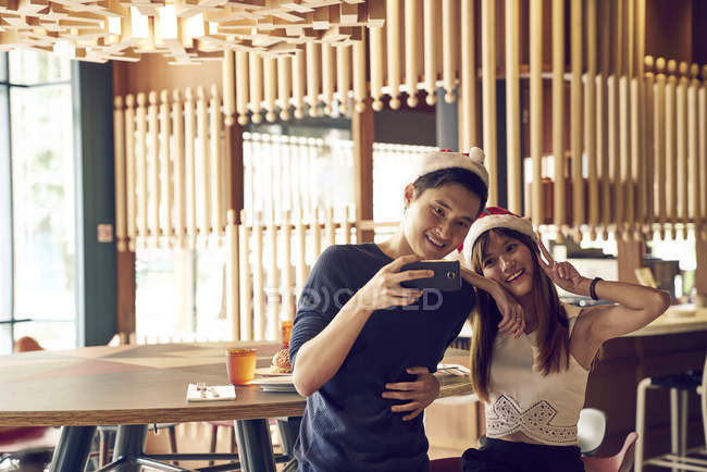 Heureux jeune asiatique couple célébrer noël ensemble dans café et prendre selfie — Photo de stock