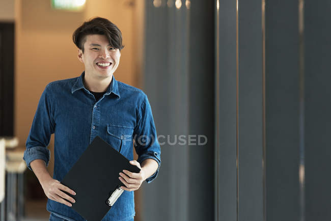 Jeune mâle asiatique travailleur avec documents dans bureau — Photo de stock