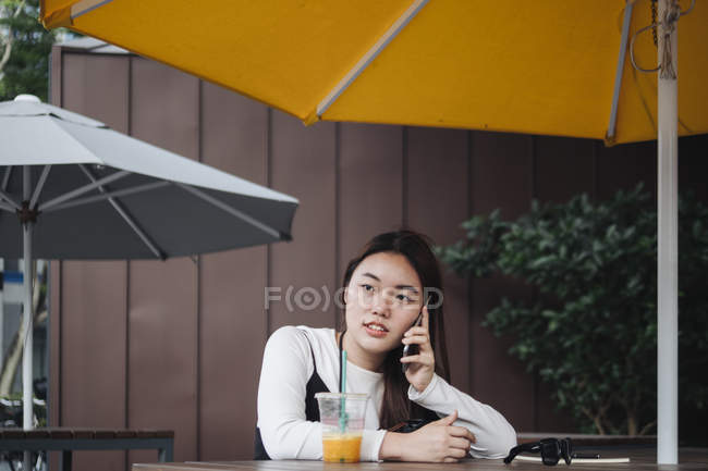 Pretty chinese long hair woman talking at smartphone in cafe — Stock Photo