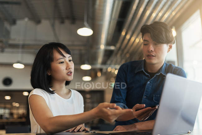 Двое молодых азиатов за работой с ноутбуком в современном офисе — стоковое фото