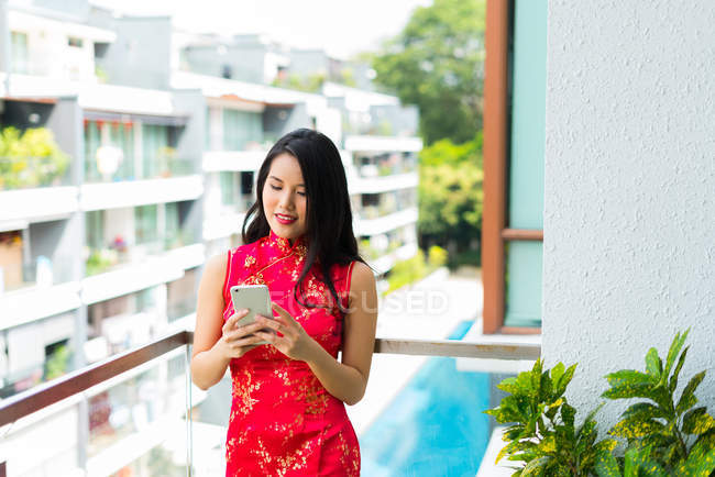 Счастливая азиатка с помощью смартфона на балконе — стоковое фото