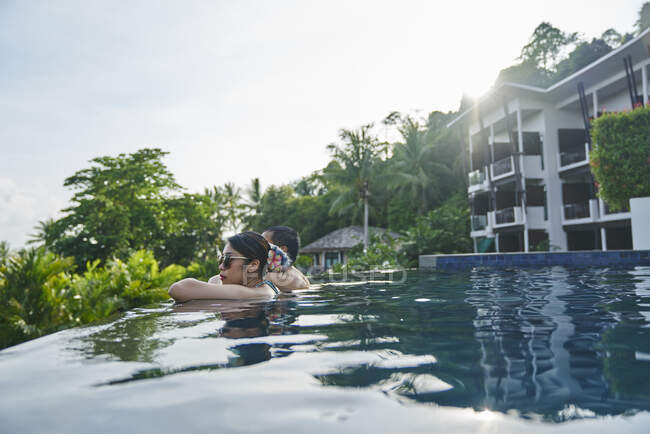 Joven pareja asiática relajándose en una piscina - foto de stock