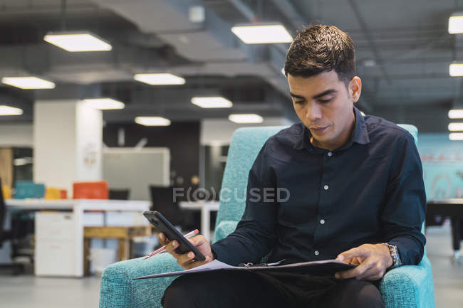 Erfolgreicher Geschäftsmann mit Smartphone im modernen Büro — Stockfoto
