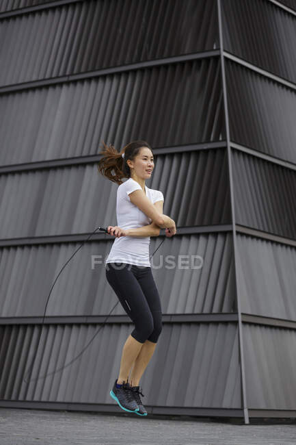Une jeune femme asiatique fait de l'exercice avec saut à la corde, en plein air à Singapour . — Photo de stock