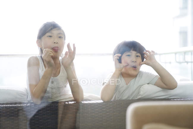 Glückliche junge asiatische Familie zusammen, Kinder machen lustige Gesichter — Stockfoto