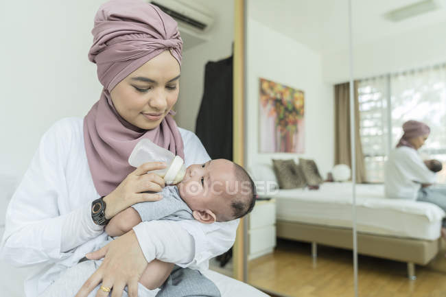 Mãe alimentando leite para seu bebê em casa — Fotografia de Stock