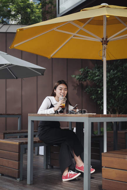 Mujer de pelo largo bastante chino sentado en la cafetería - foto de stock