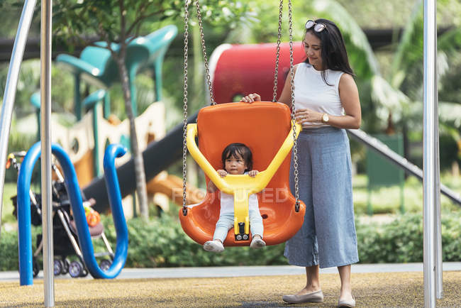 Mignonne adorable asiatique petite fille sur aire de jeux avec mère — Photo de stock