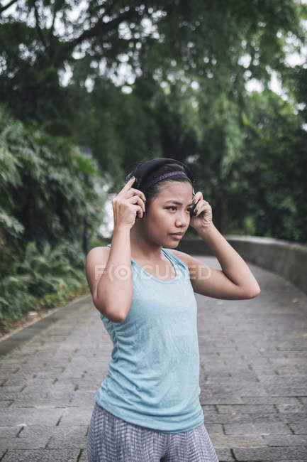 Молода азіатська спортивна жінка в навушниках у парку — стокове фото