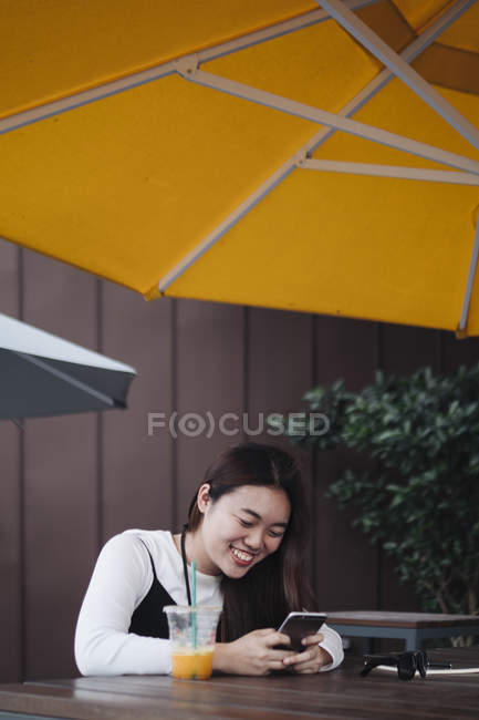 Красивая китайская женщина с длинными волосами с помощью смартфона в кафе — стоковое фото