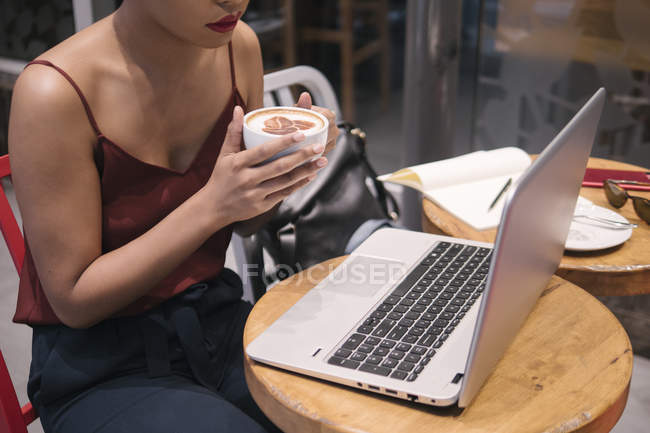 Cropped image of young attractive asian woman using laptop in cafe — Stock Photo