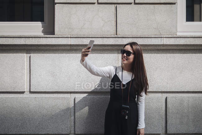 Bastante chino largo cabello mujer tomando selfie en calle - foto de stock