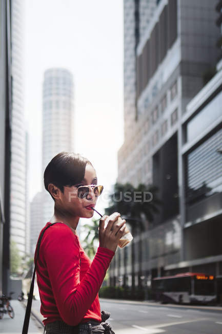 Молода азіатська приваблива жінка п'є каву на міській вулиці — стокове фото