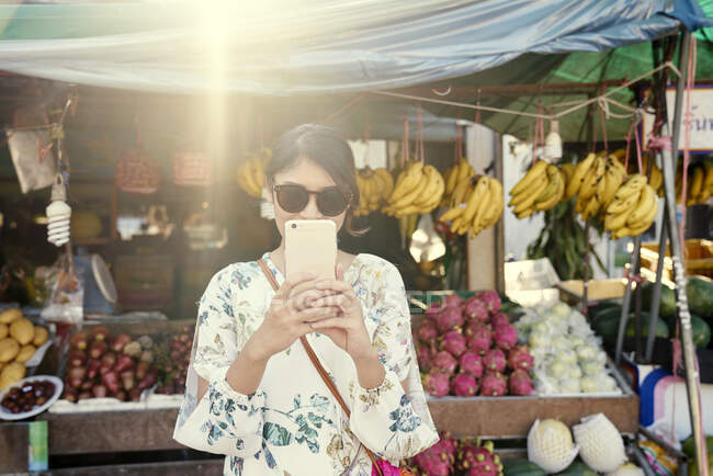 Jovem mulher tirando fotos de uma barraca de frutas de rua em Koh Chang, Tailândia — Fotografia de Stock