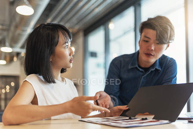 Two young asian people at work with documents in modern office — Stock Photo