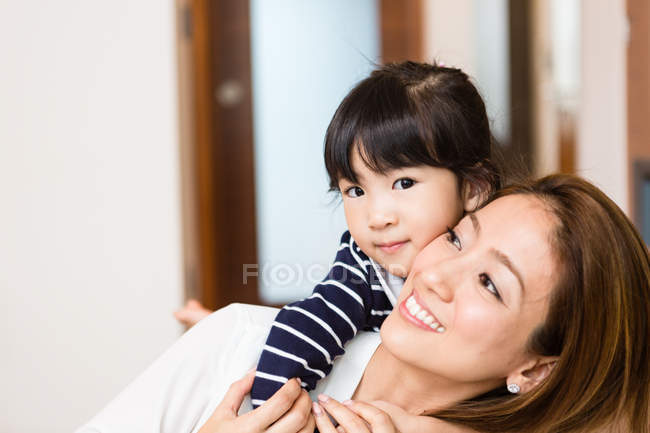 Daughter hugging mom from behind at home — Stock Photo
