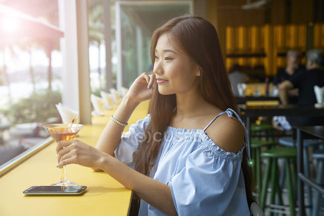 Atractivo joven asiático mujer con bebida en café - foto de stock