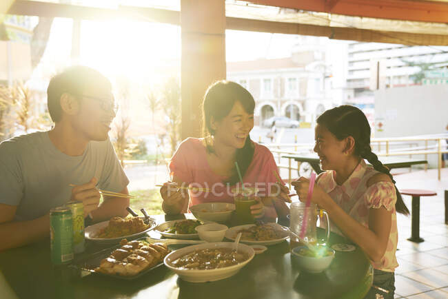 Счастливая молодая азиатская семья ест вместе в кафе — стоковое фото