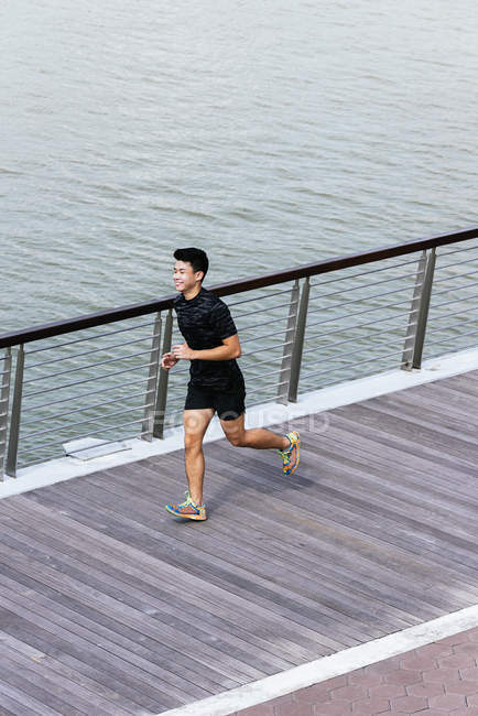 Sportlicher junger Mann läuft auf Seebrücke — Stockfoto