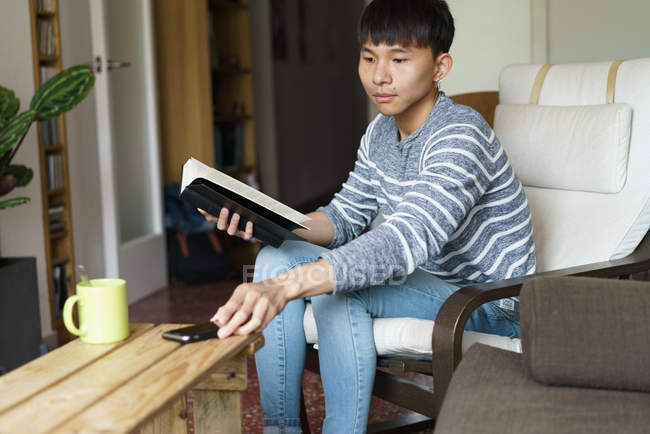 Дорослий азіатських юнак за допомогою смартфона в домашніх умовах — стокове фото