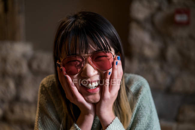 Молодая случайная азиатская девушка, улыбающаяся в солнечных очках — стоковое фото