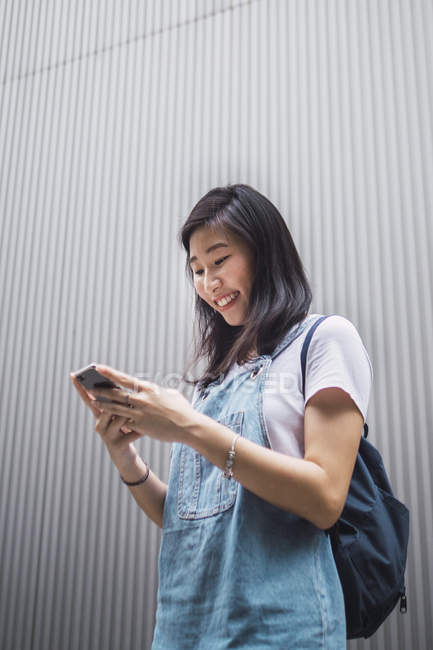 Giovane asiatico college studente utilizzando smartphone — Foto stock