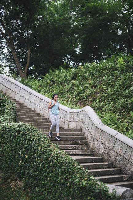 Jovem asiático mulher desportiva correndo em escadas no parque — Fotografia de Stock