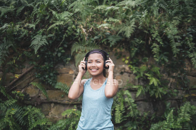Joven asiático deportivo mujer usando auriculares en parque - foto de stock