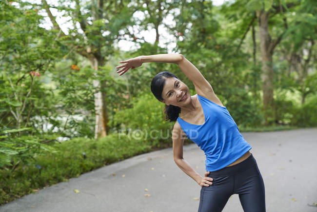 Middle-aged woman warming up in Botanic Gardens before her run — Stock Photo
