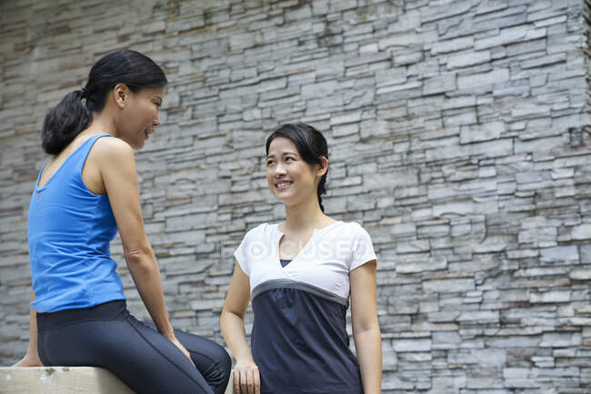 Dos mujeres poniéndose al día antes de su entrenamiento en Botanic Gardens, Singapur - foto de stock