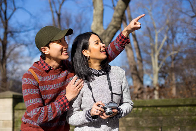 Couples touristiques attrayants marchant dans le parc, homme pointant — Photo de stock