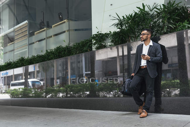 Handsome indian business man using smartphone on city street — Stock Photo
