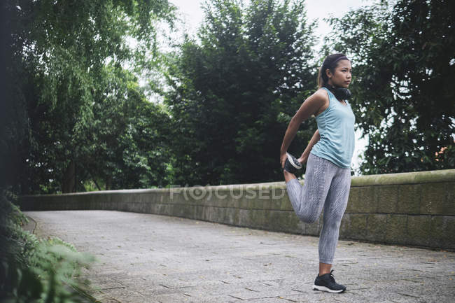 Young asian sporty woman making stretching in park — Stock Photo