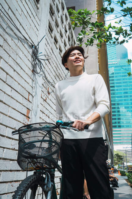 Jovem homem de negócios asiático na cidade com bicicleta — Fotografia de Stock